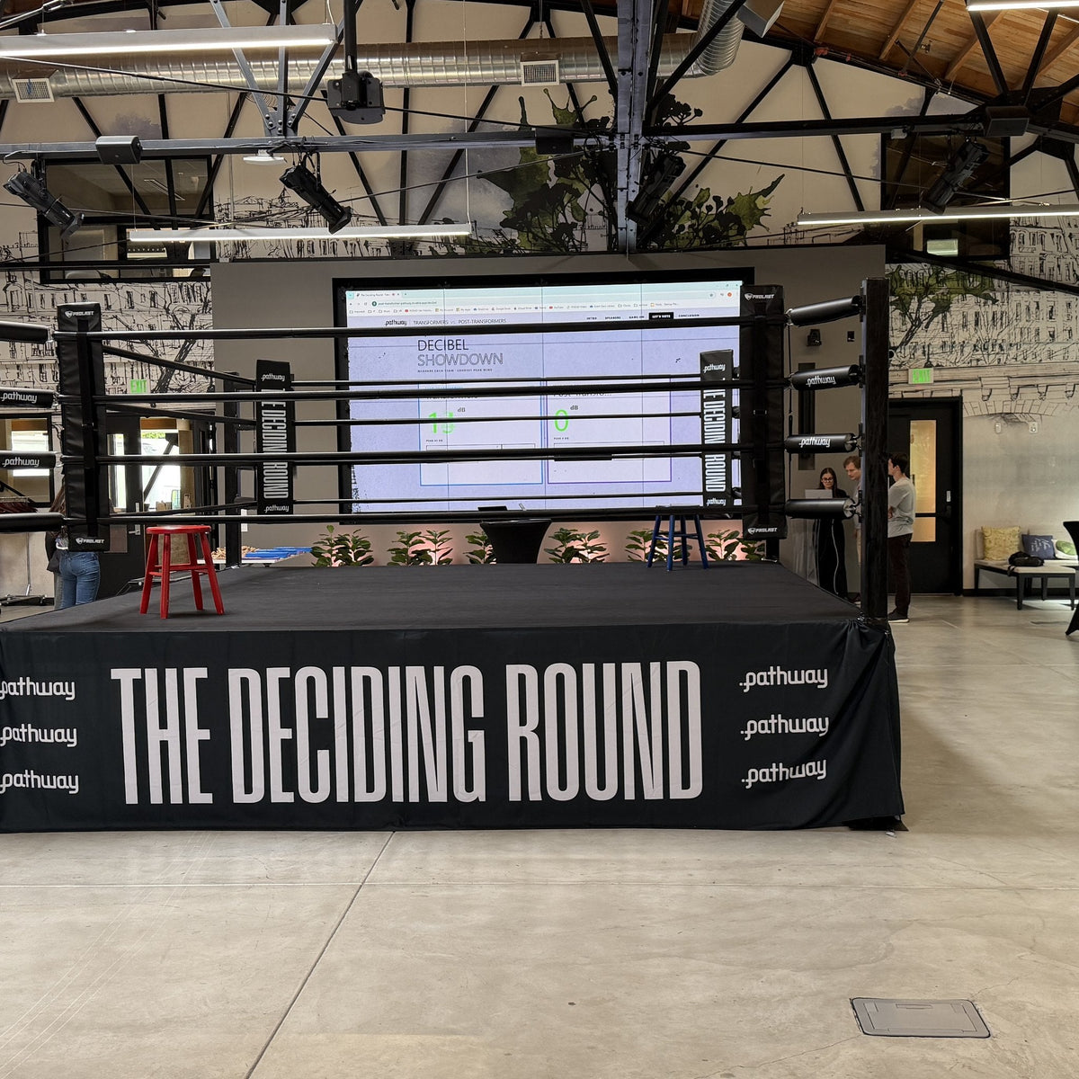 PROLAST boxing ring with black ropes and a printed skirt in an event hall