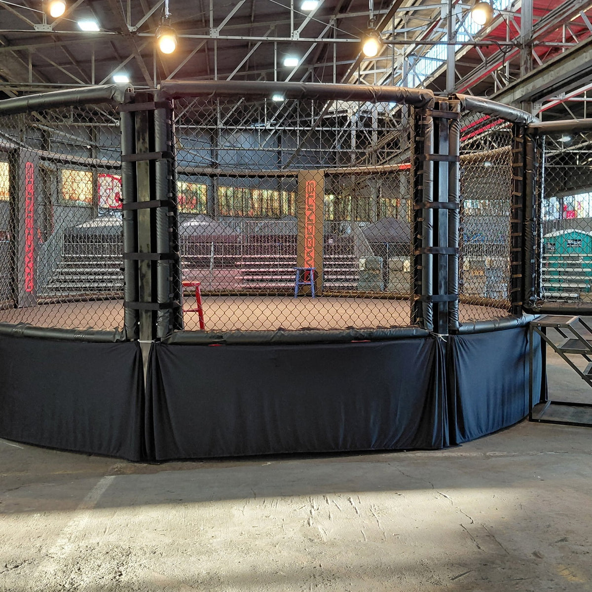 PROLAST MMA cage with a black skirt and stairs in a warehouse