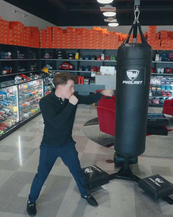 A man jabbing and punching a black 4 ft PROLAST heavy bag on a bag stand