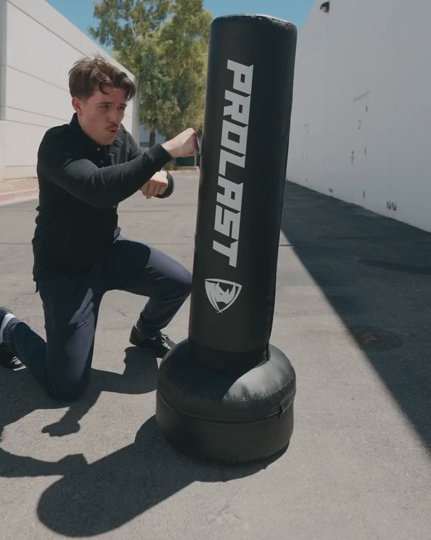 A man kneeling to throw body shots into a 4 ft PROLAST freestanding bag