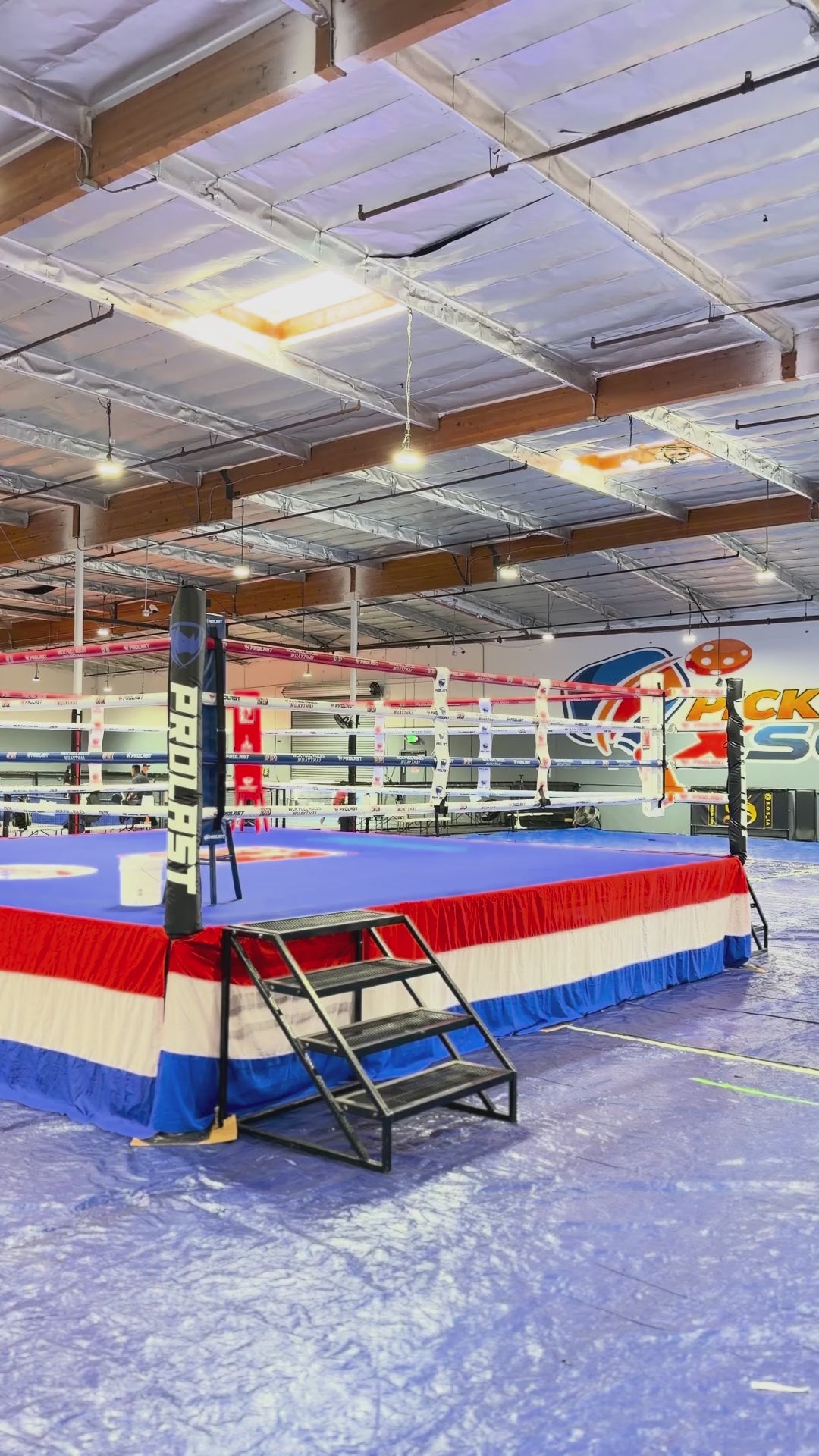 PROLAST boxing ring with a red, white and blue skirt and stairs at a Muay Thai event