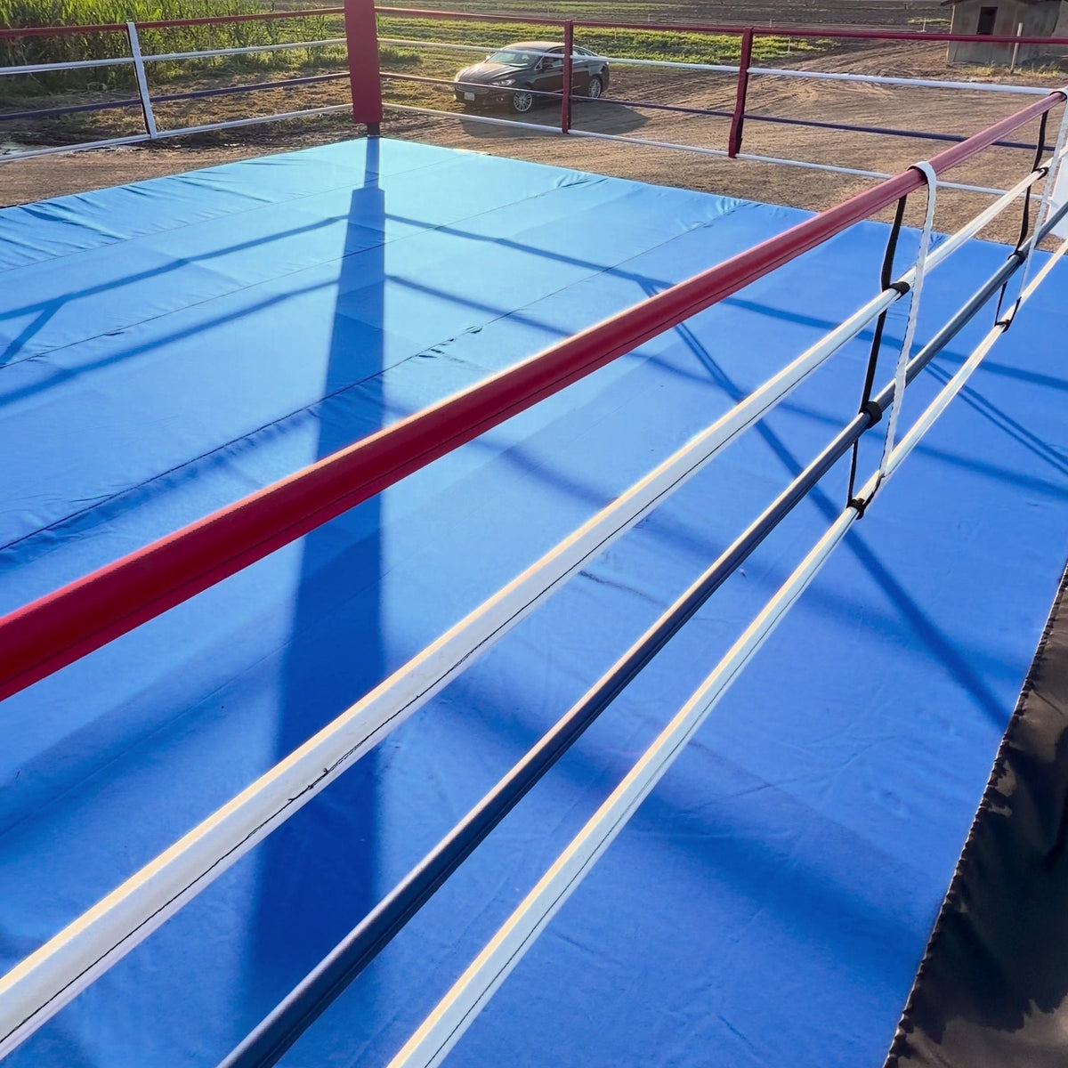 Corner of a PROLAST boxing ring with a blue canvas outdoors in the sun