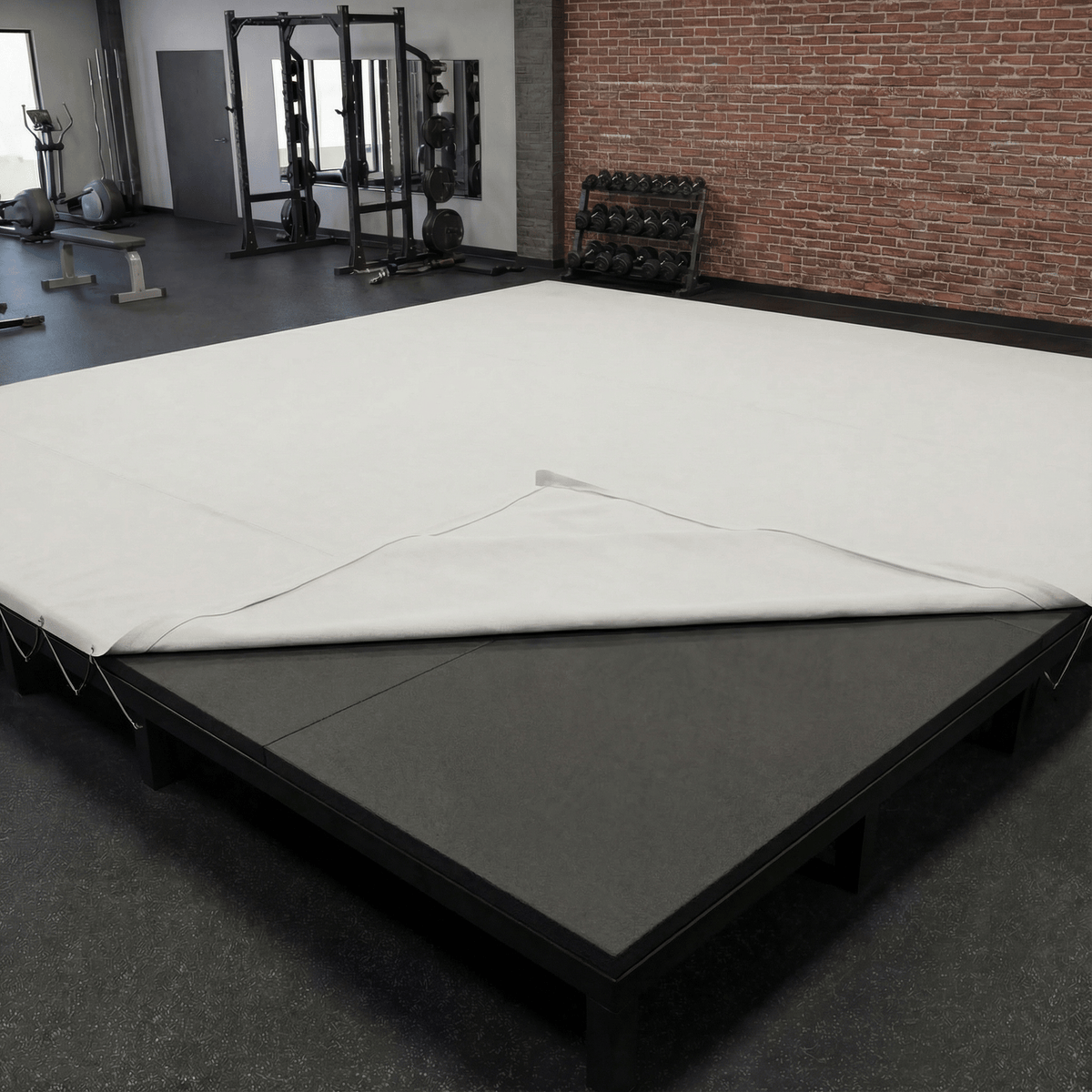 PROLAST boxing ring padding laid on a ring platform, the white canvas folded back at one corner