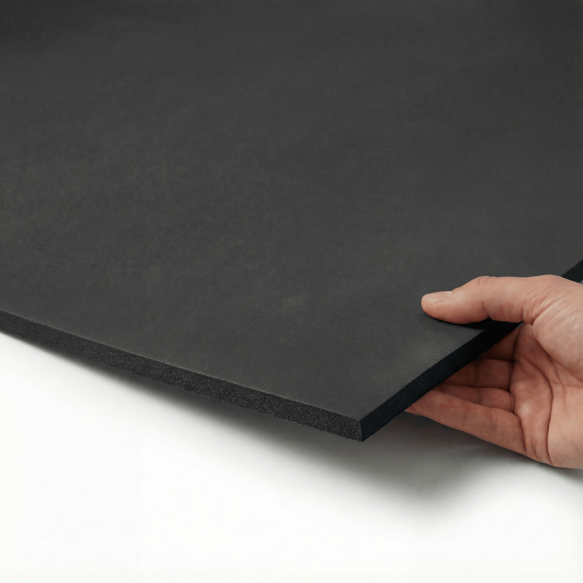 PROLAST boxing ring padding: a black foam sheet lifted at the edge by hand to show its thickness