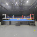PROLAST boxing ring with red, white and blue ropes and stairs in a black studio