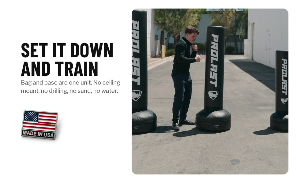 Set it down and train: a person training among black PROLAST freestanding bags outdoors. Bag and base are one unit, with no ceiling mount, drilling, sand or water