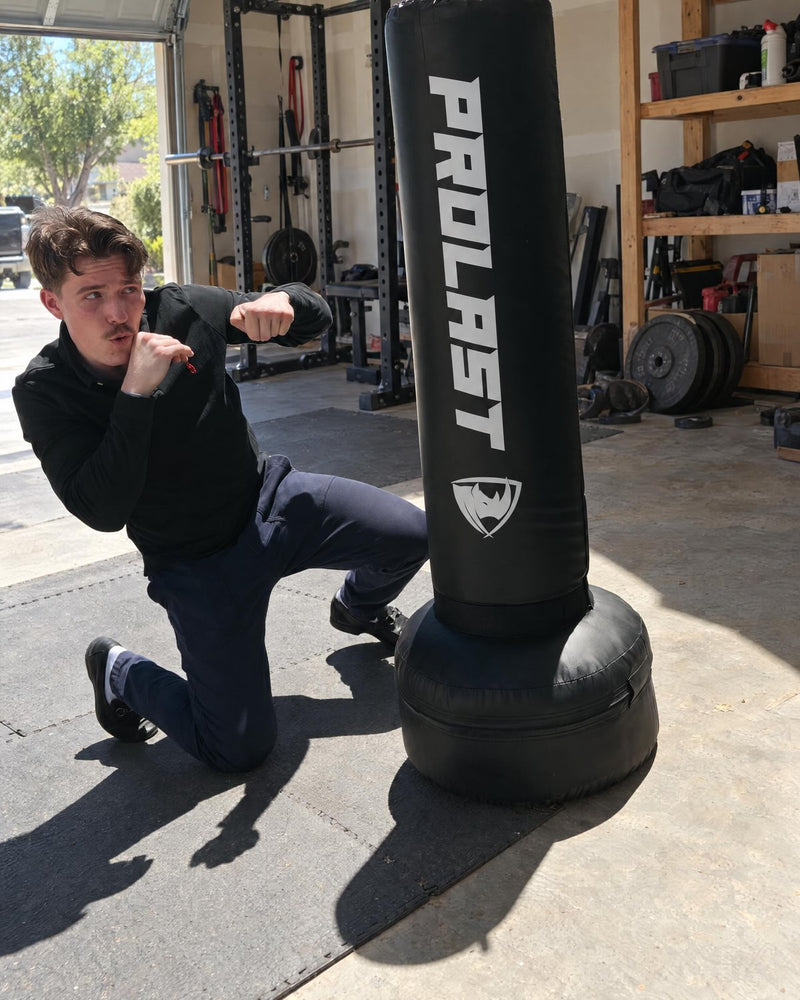 A man throwing a low punch at the 4 ft freestanding bag in a garage gym